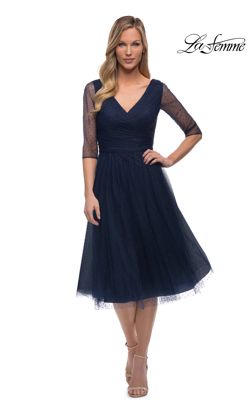 Woman wearing a navy blue dress with sheer sleeves on a white background