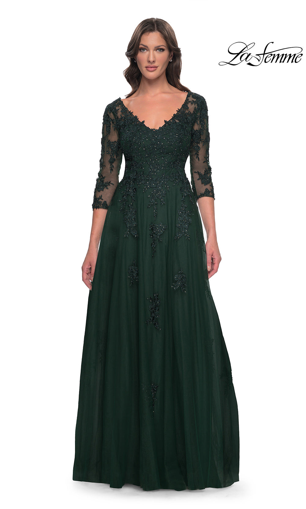 Woman wearing a dark green evening gown with lace detailing on a white background