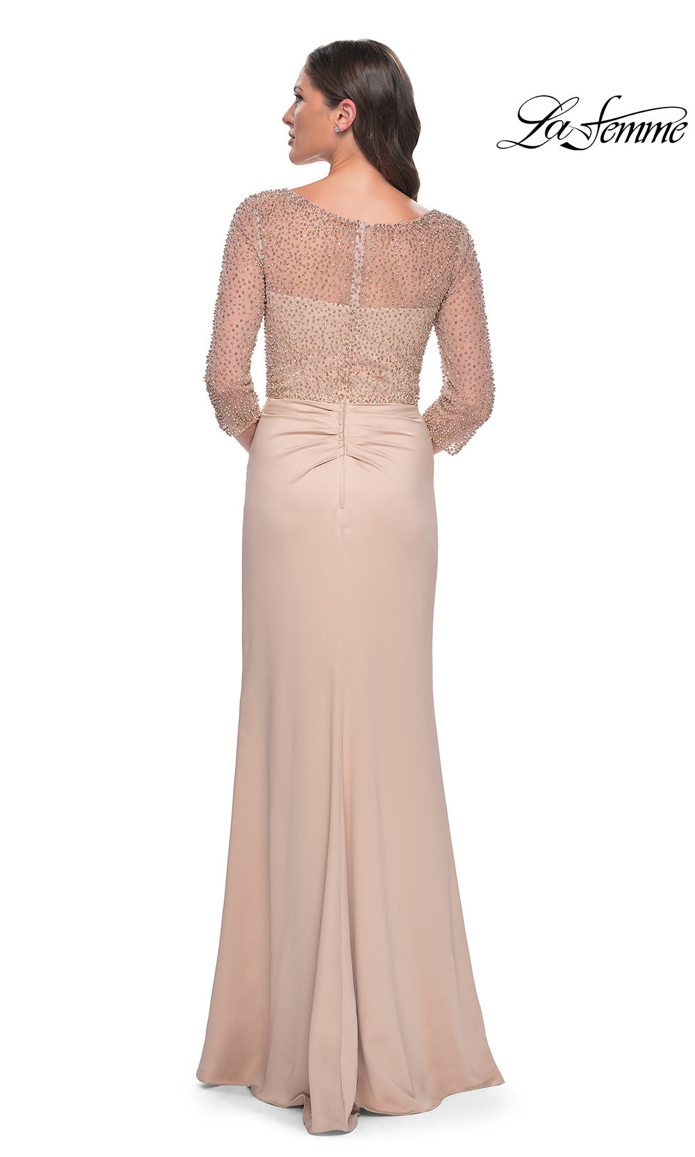 Woman wearing a beige evening gown with a sheer top on a white background