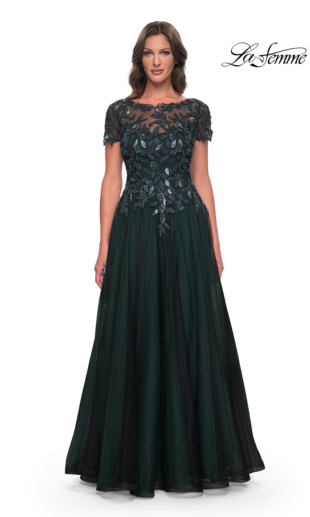 Woman wearing a dark green evening gown with lace detailing on a white background