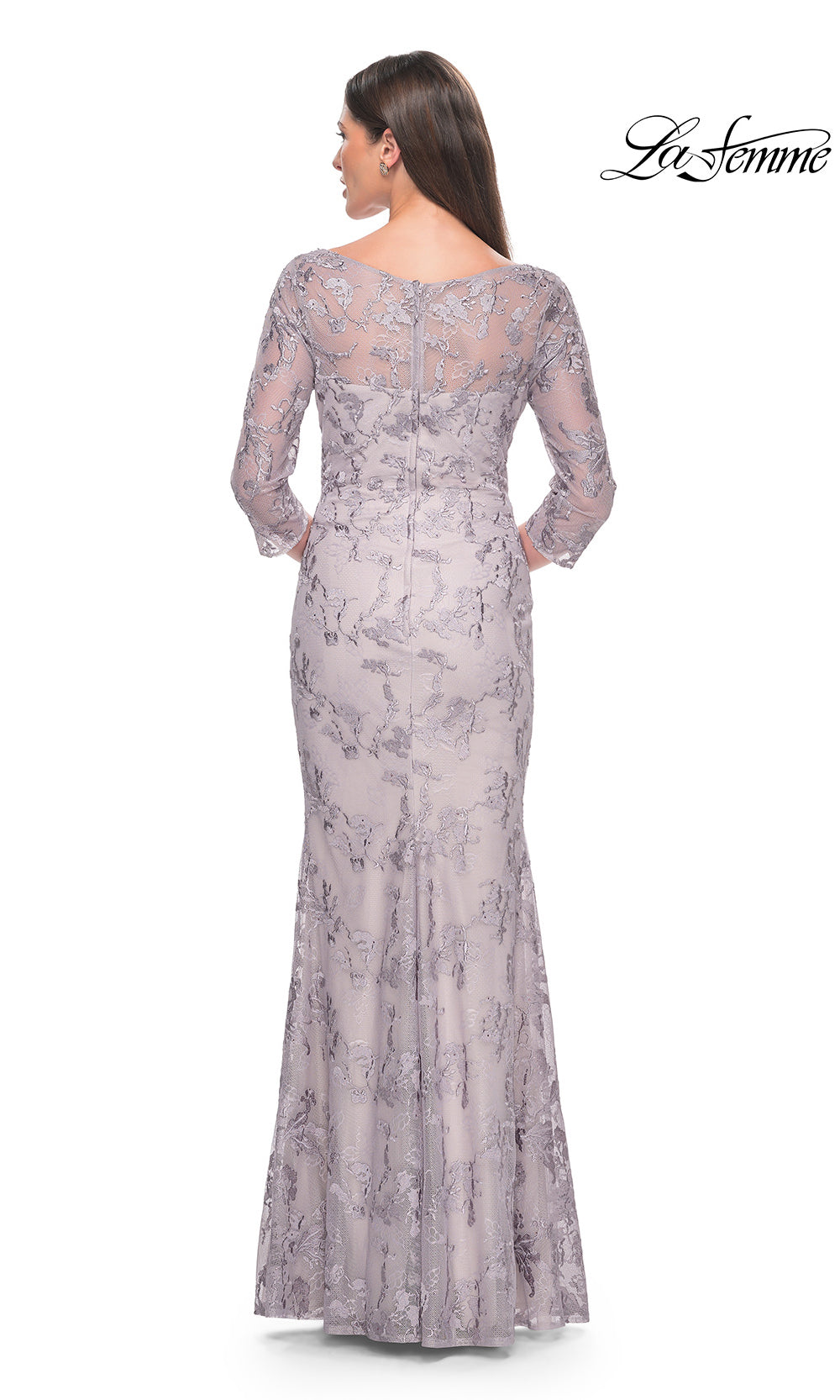 Woman wearing a long, patterned dress with a lace overlay on a white background.