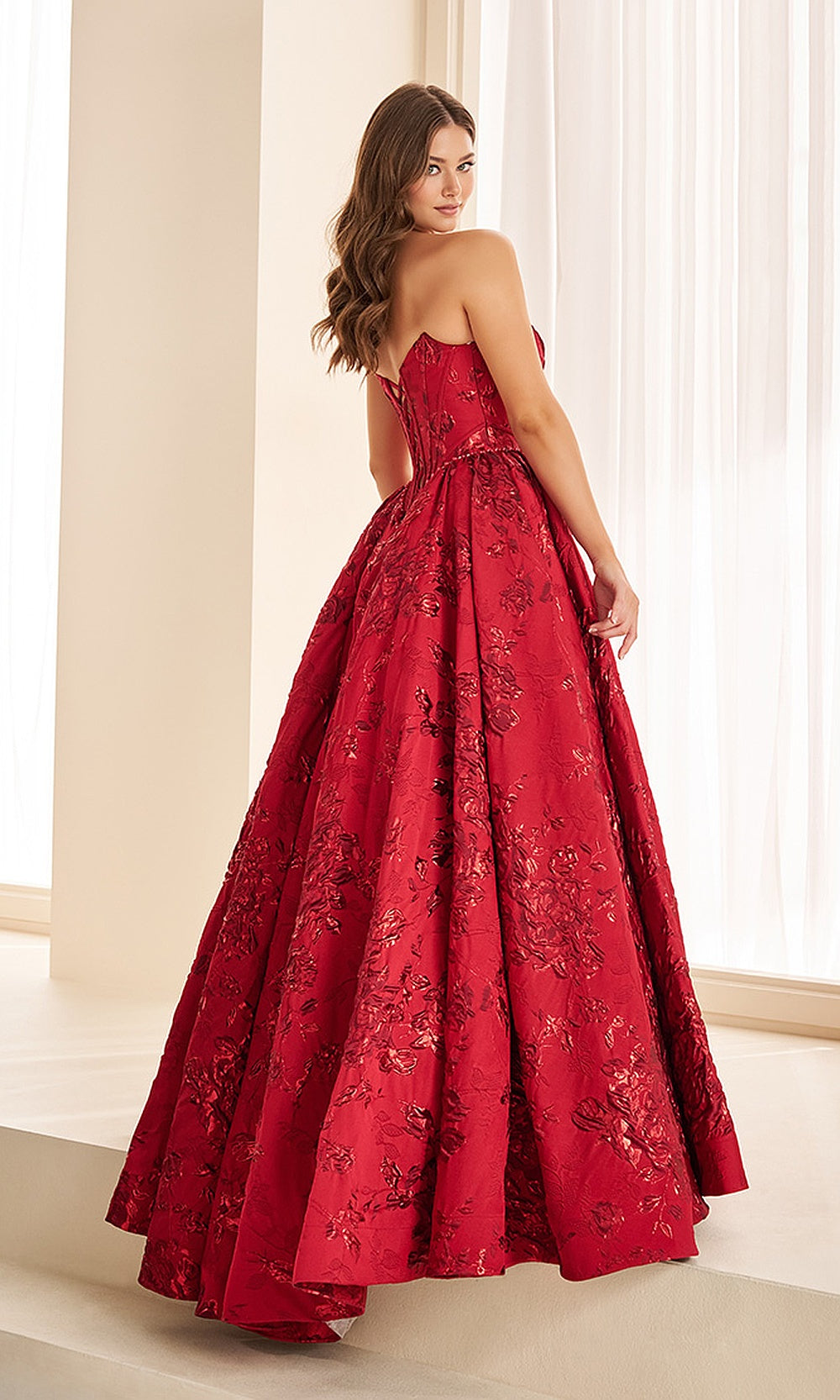 Ellie Wilde EW38100 Red prom dress back view with jacquard print fabric, lace-up corset back, boning detail, and sweeping train ballgown silhouette, pageant-ready gown.
