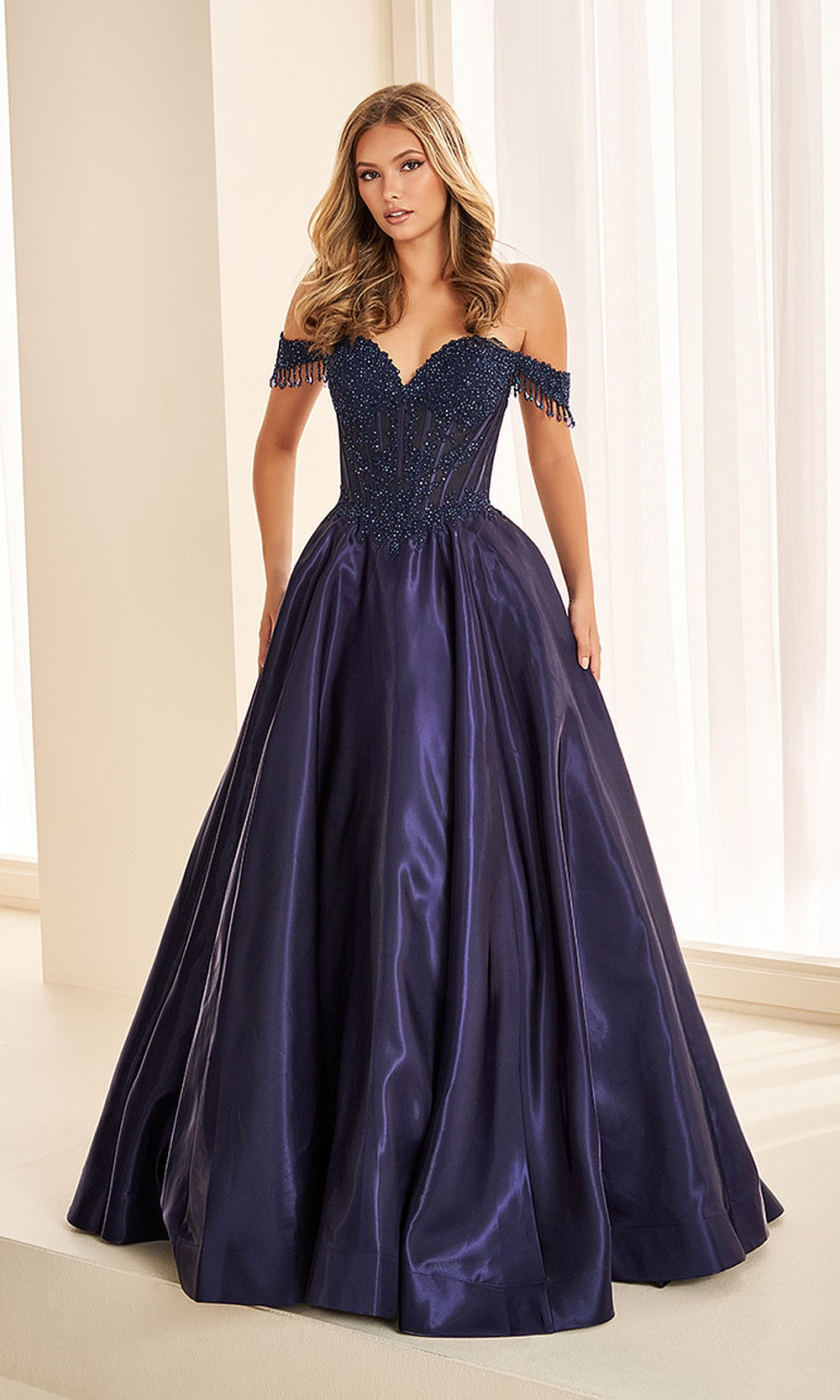 Ellie Wilde EW38128 Navy Blue off-shoulder prom dress front view with satin and lace, beading and floral appliques, a-line ballgown silhouette, black tie event dress.