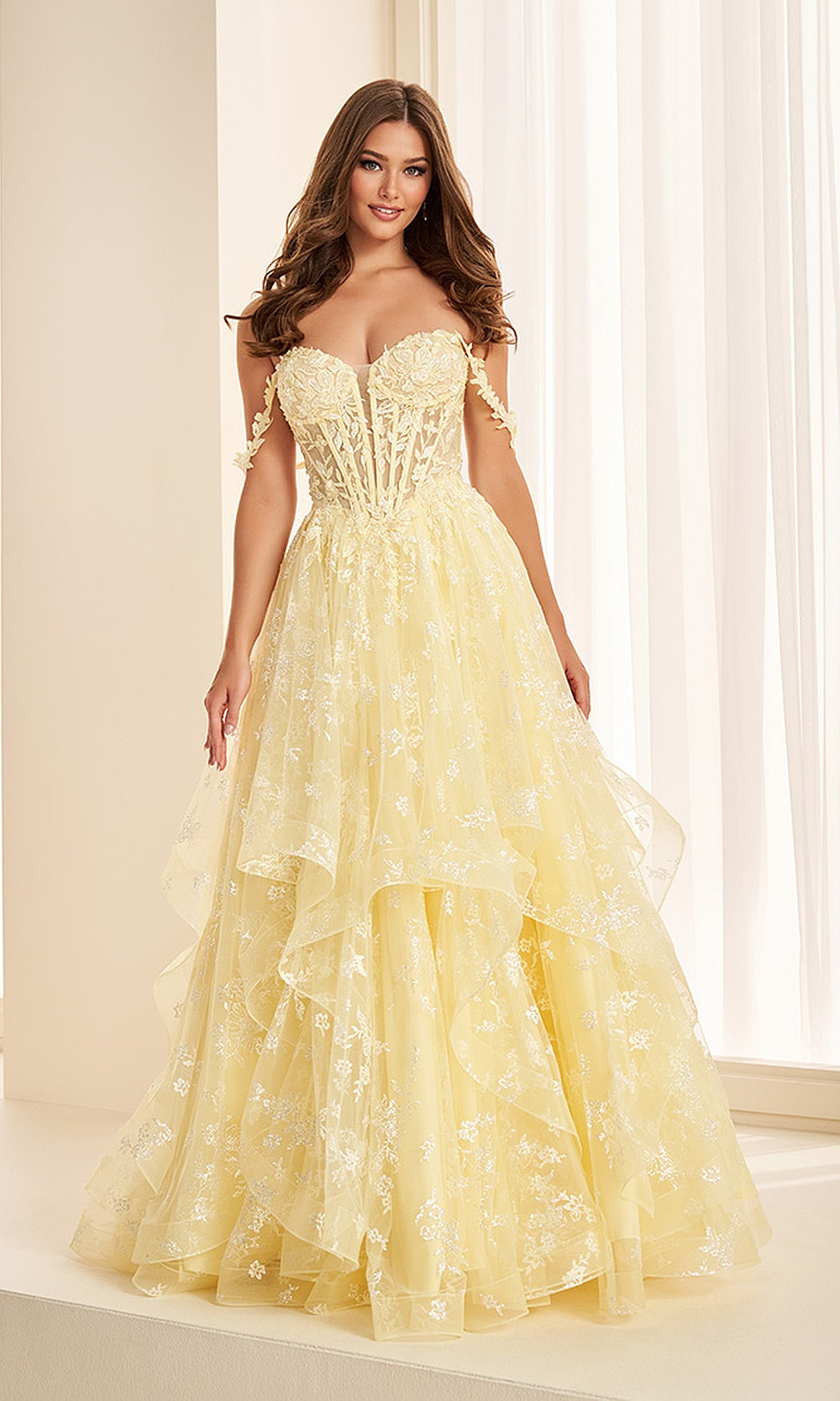 Ellie Wilde EW38204 Light Yellow prom dress front view with glitter tulle and lace, floral appliques, sweetheart corset bodice, and voluminous ruffle ballgown skirt, gala gown.