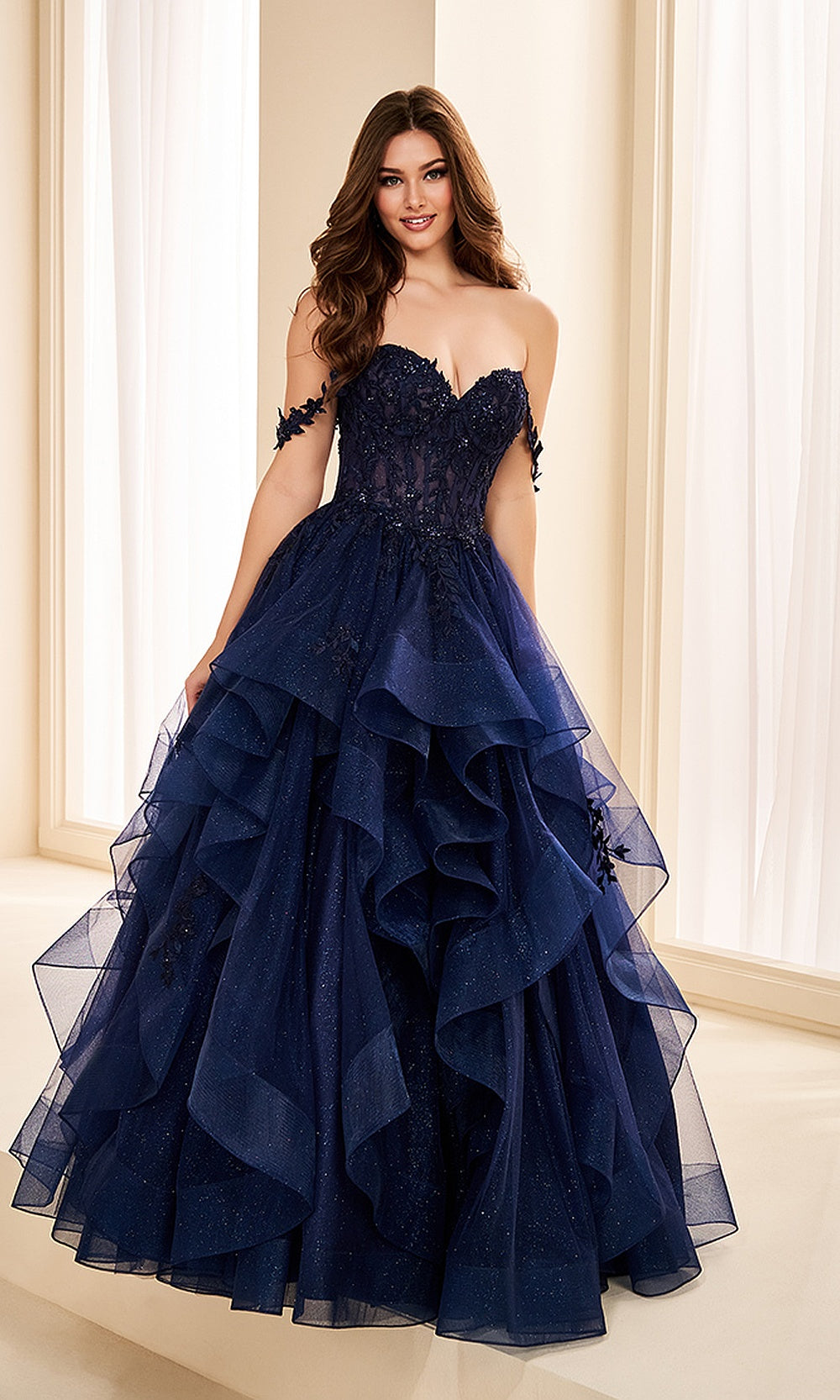 Ellie Wilde EW38220 Navy Blue off-shoulder corset prom dress front view with glitter tulle and lace, floral appliques and boned bodice, ballgown silhouette, evening gown.