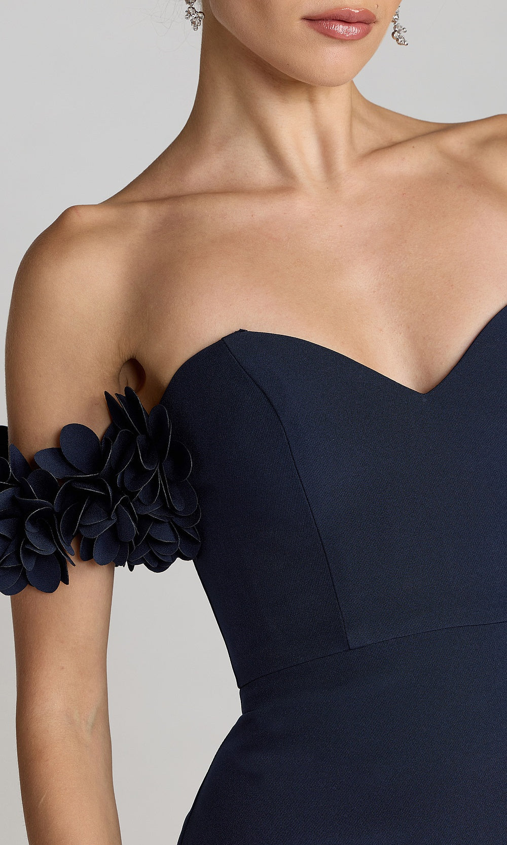 Mac Duggal 56131 midnight-blue detail view prom gown showing 3D floral petal clusters, boned side-seam bodice panels, off-shoulder sweetheart construction