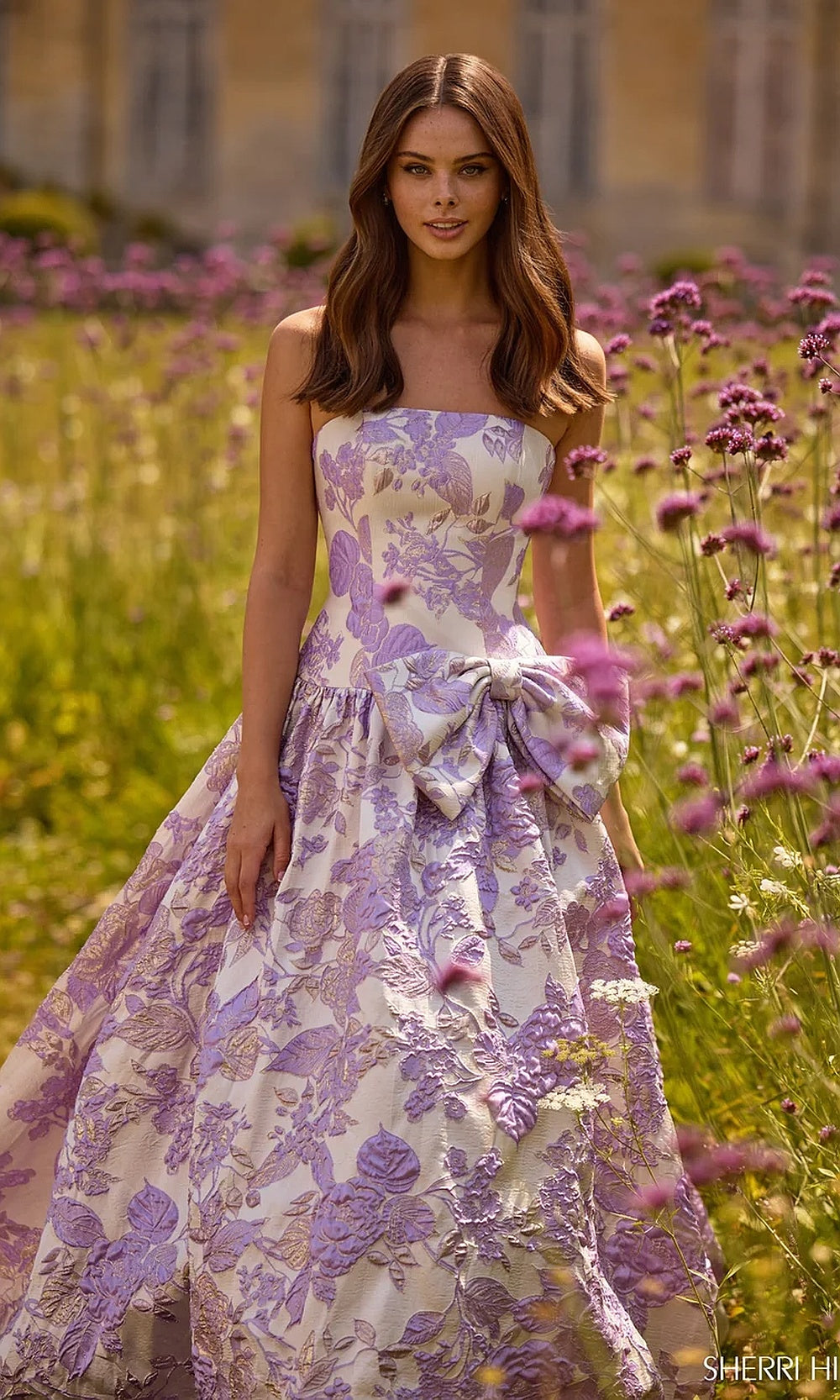 Sherri Hill 57730 Ivory Lilac strapless floral jacquard ballgown prom dress with a-line silhouette, fabric waist bow and train, editorial view, quinceañera gown