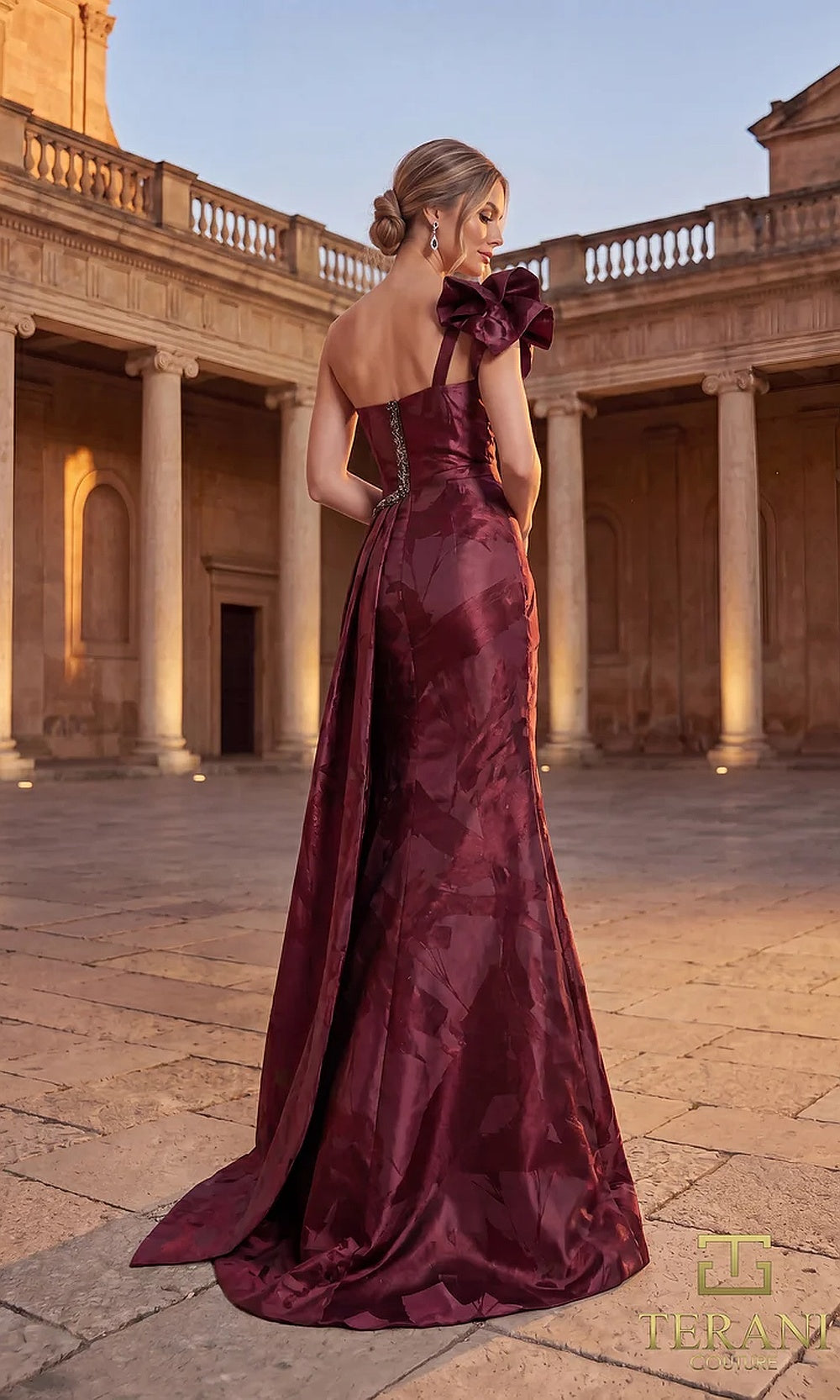 Terani Couture 262E7376 Burgundy formal evening dress back view with one-shoulder ruffle bow, tonal jacquard A-line with sweep train, gala gown