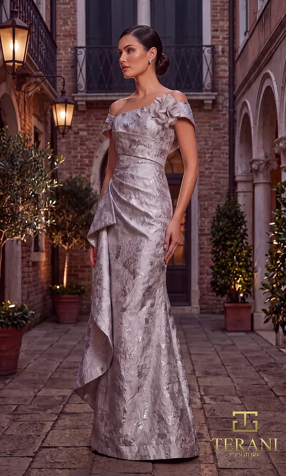 Terani Couture 262M7298 Silver mother of the bride dress front view with off-shoulder folded neckline with rosette, draped metallic brocade fitted mermaid with side cascade, mother of the bride styling